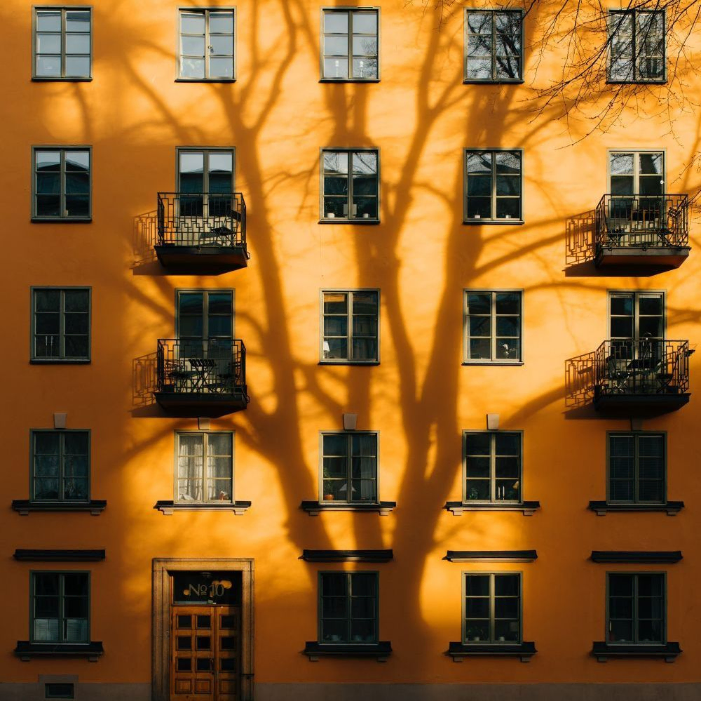 orange husfasad med skugga av träd